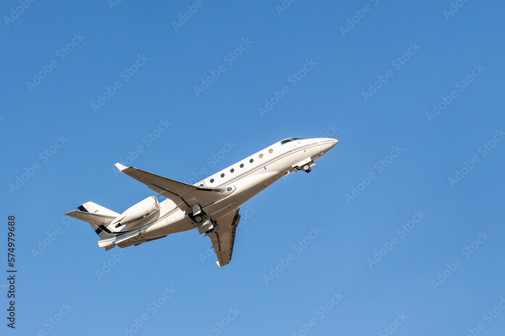 Scenic close bottom view modern luxury expensive white private jet plane dispatching from airport isolated on blue clear sky background. Executive aicraft vip travel concept. Service and maintenance Scenic close bottom view modern luxury expensive white private jet plane dispatching from airport isolated on blue clear sky background. Executive aicraft vip travel concept. Service and maintenance