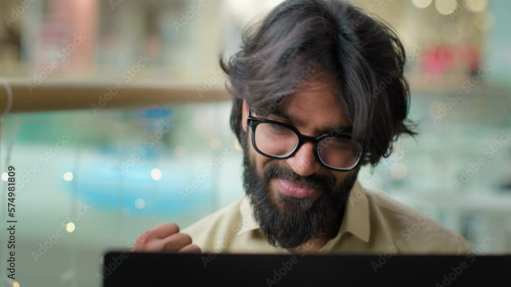 Happy executive Indian bearded entrepreneur man in glasses celebrate win with laptop achievement talk video call shout with success. Arabian businessman winning business goal achieve online victory Happy executive Indian bearded entrepreneur man in glasses celebrate win with laptop achievement talk video call shout with success. Arabian businessman winning business goal achieve online victory