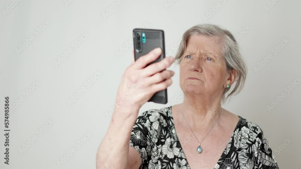 Senior woman confused while holding mobile phone over white background Senior woman confused while holding mobile phone over white background