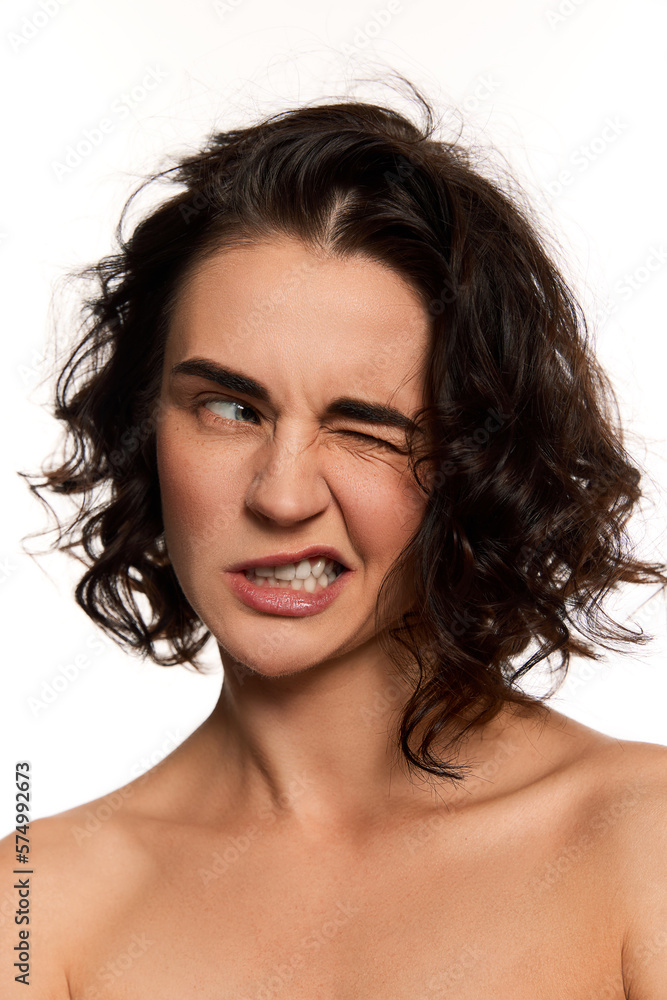 Emotional beautiful young woman with bare shoulders make grimace over white background. Fashion, beauty, spa, cosmetology, skincare concept