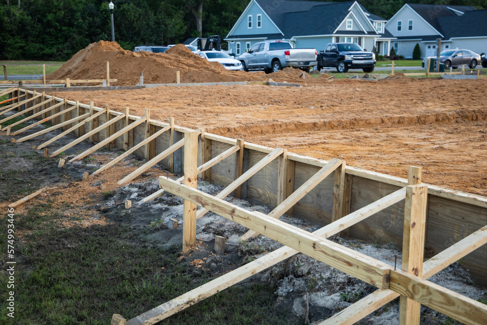 Obraz premium The beginning of a new construction build in a neighborhood with the foundation poured, dirt added and the wood based began