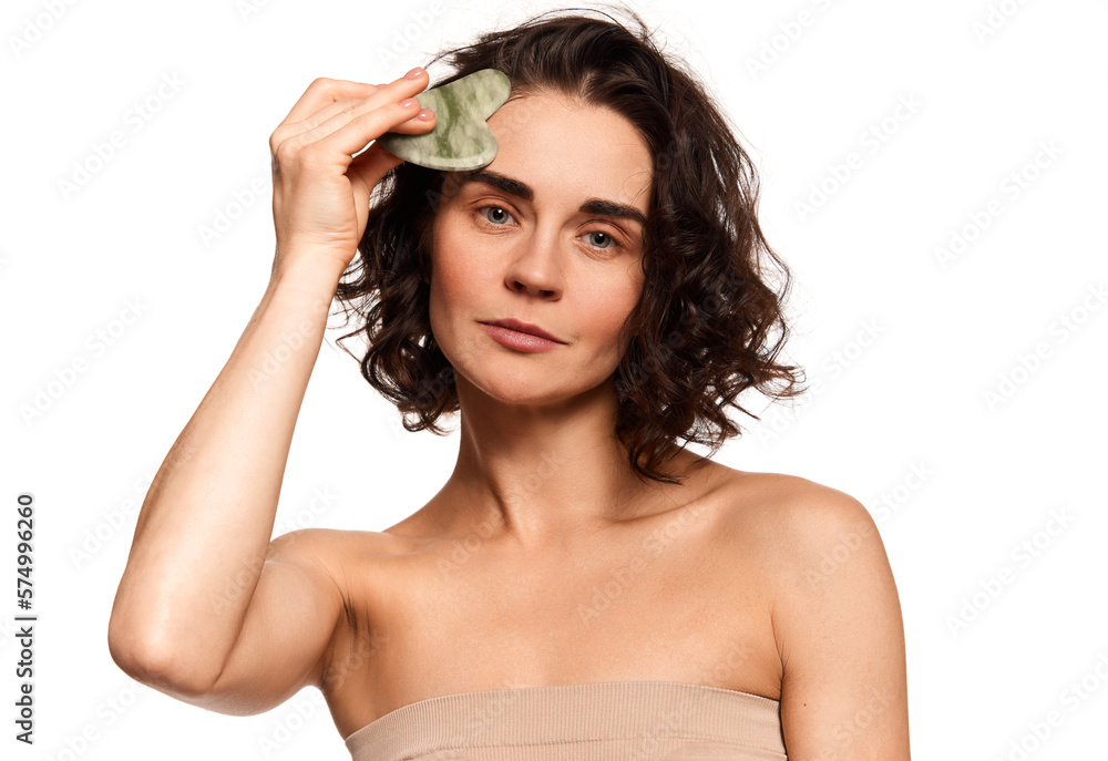 Young beautiful woman taking care after face skin, doing anti-aging procedures with special cosmetical tools over white studio background. Young beautiful woman taking care after face skin, doing anti-aging procedures with special cosmetical tools over white studio background.