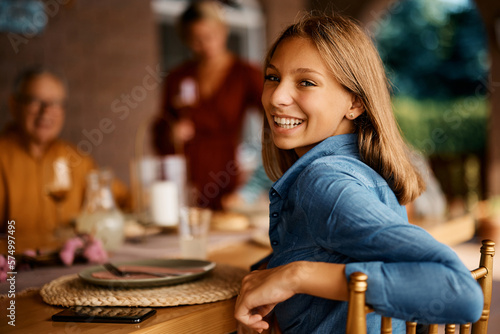 Happy teenage girl enjoys in family lunch on terrace and looking at camera.