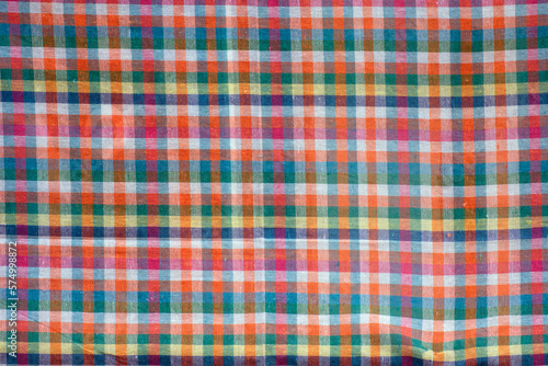 Colorful checkered tablecloth as background, top view.