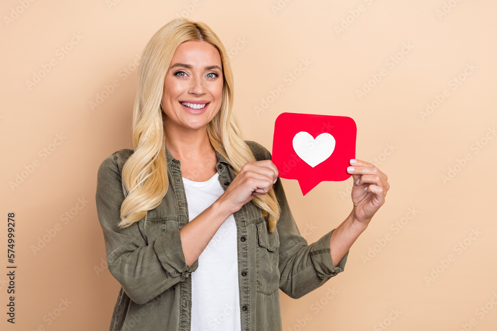 Photo of positive sweet woman wear khaki shirt holding feedback card isolated beige color background Photo of positive sweet woman wear khaki shirt holding feedback card isolated beige color background