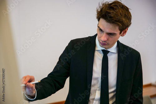 A young man is drawing something on an interactive whiteboard