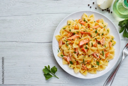 Bild auf Leinwand Italian Traditional DishFarfalle al Salmone,farfalle pasta with smoked salmons,onions,olive oil,parsley,salt and peppers on plate with white wood table background
