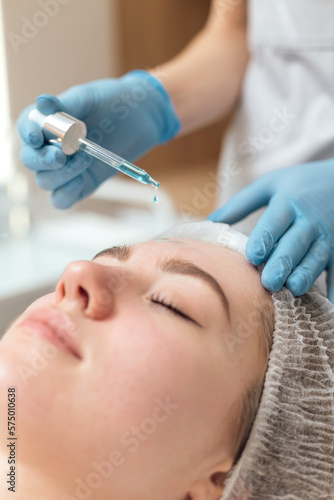 Beautician applies cleanser and moisturizer to the face with a dropper