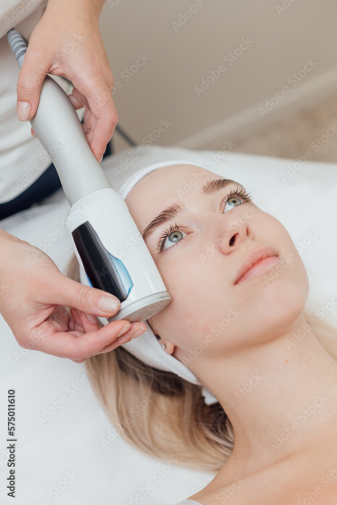 Naklejka premium Cosmetologist uses device on a female face