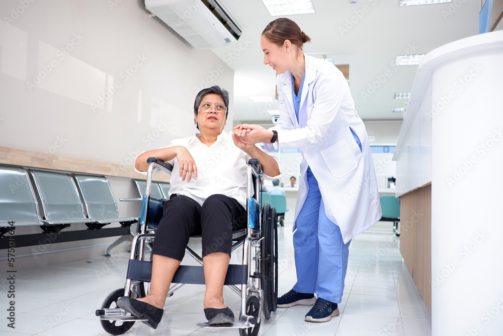 Smiling female doctor caring for an elderly female patient sitting in a wheelchair inside a hospital medical concept. Smiling female doctor caring for an elderly female patient sitting in a wheelchair inside a hospital medical concept.