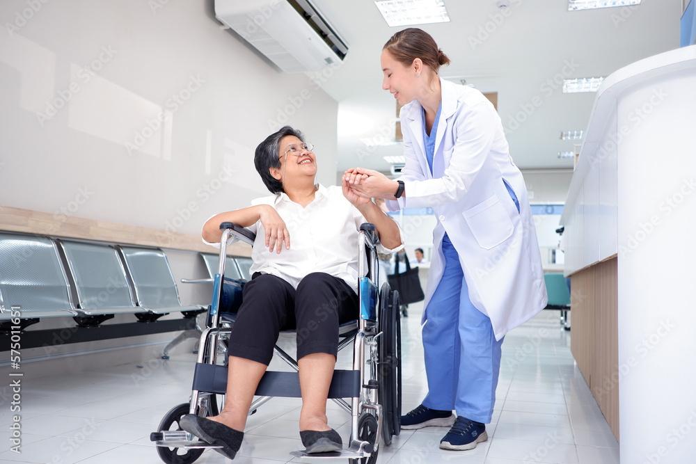 Smiling female doctor caring for an elderly female patient sitting in a wheelchair inside a hospital medical concept. Smiling female doctor caring for an elderly female patient sitting in a wheelchair inside a hospital medical concept.