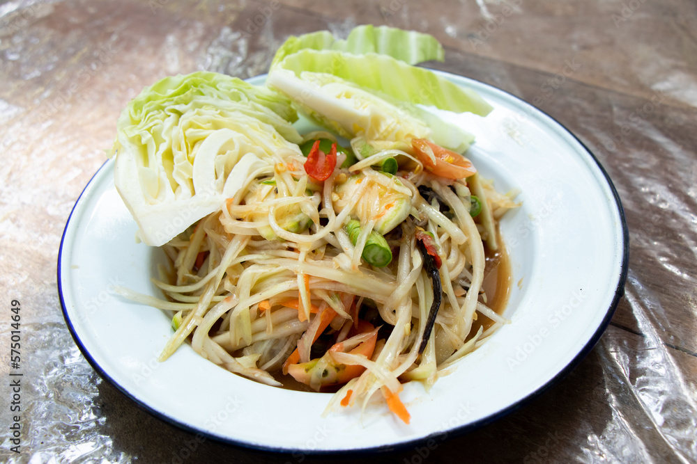 Thai papaya salad (Somtum) in white plate on wooden table