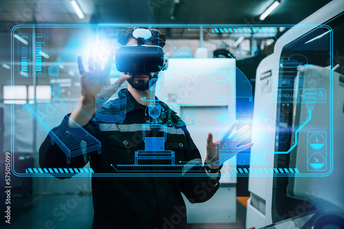 Engineering male wearing VR glasses for simulate control automation robotic arm welding machines in modern factory warehouse. Innovation artificial intelligence technology for industrial revolution.