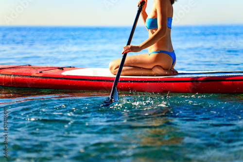 Woman sitting on sup board and enjoying peace and quiet outdoors © yurakrasil