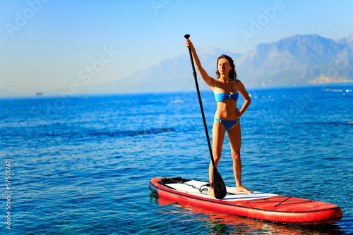 sporty fitness woman on SUP board at sunny nice day on sea