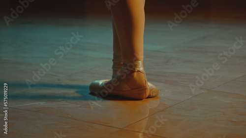 Cinematic close up shot of classical ballet dancer feet in pointe shoes. Female dancer on choreography rehearsal in opera. Professional ballerina trains moves before start a show. Graceful ballet art.