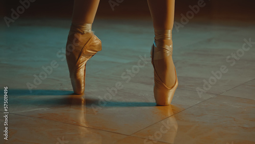 Cinematic close up shot of graceful ballet dancer feet in pointe shoes and white tutu. Female dancer on choreography rehearsal in opera. Ballerina trains moves before a show. Classical ballet art.