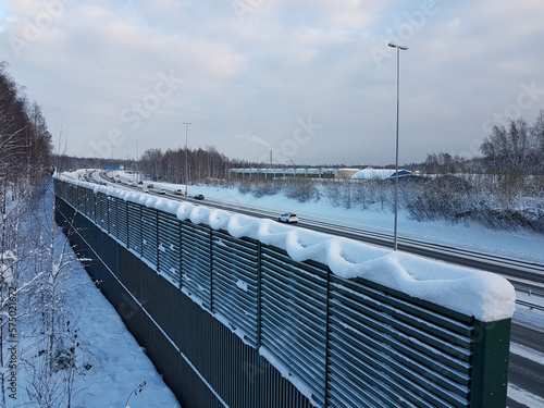 Nature-made snow art on top of a noise cancelling fence next to a highway at winter photo