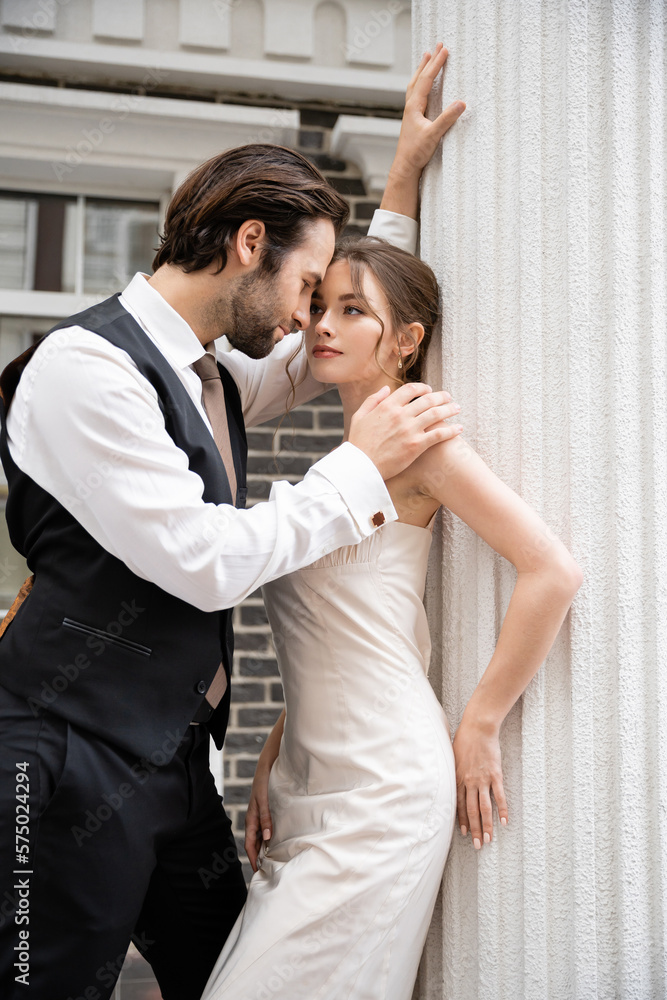 bearded groom in formal wear touching shoulder of pretty bride in wedding dress. bearded groom in formal wear touching shoulder of pretty bride in wedding dress.