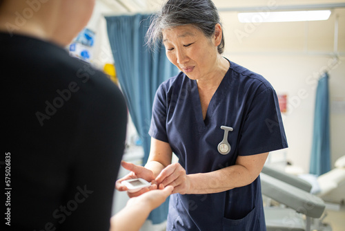 Health worker getting a blood sample from a woman using a blood lancet in the clinic