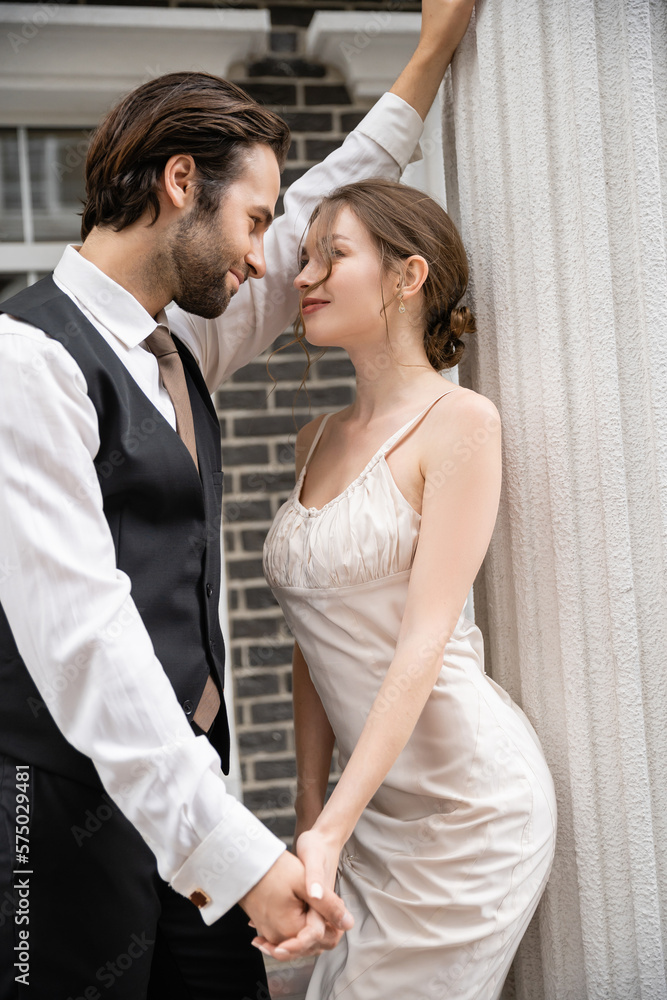 groom in formal wear and bride in wedding dress holding hands while looking at each other. groom in formal wear and bride in wedding dress holding hands while looking at each other.