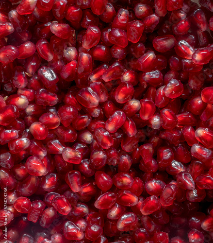 Pomegranate seeds with water droplets glisten in the light. Solid texture of pomegranate seeds. Closeup.