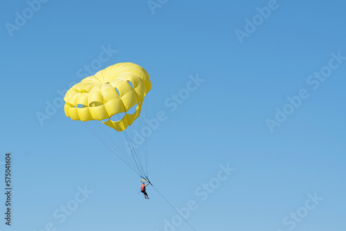 Yellow parachute with man flight in blue sky