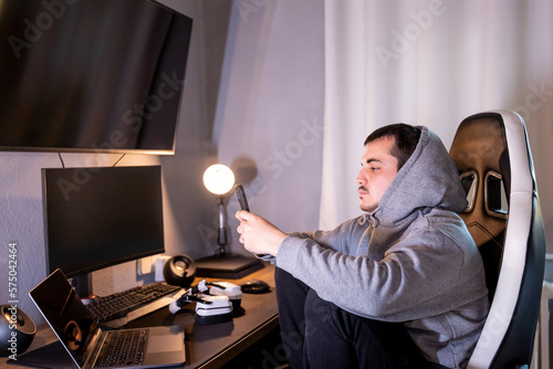 young man anguished by being surrounded by so much technology, the mobile phone generates anxiety,
looking at the phone sad, mental health concept photo