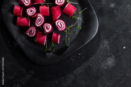 Thin red pancakes. Rolls of beetroot pancakes with cream cheese