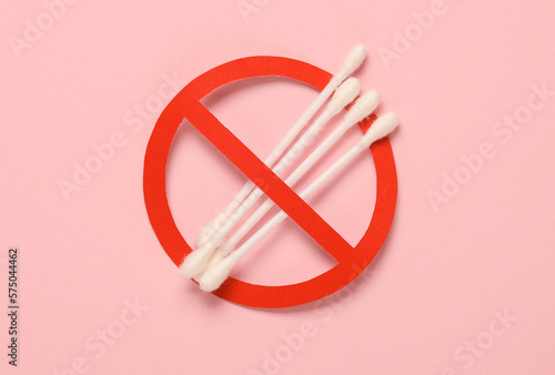 Cotton ear buds with a prohibition sign on a pink background