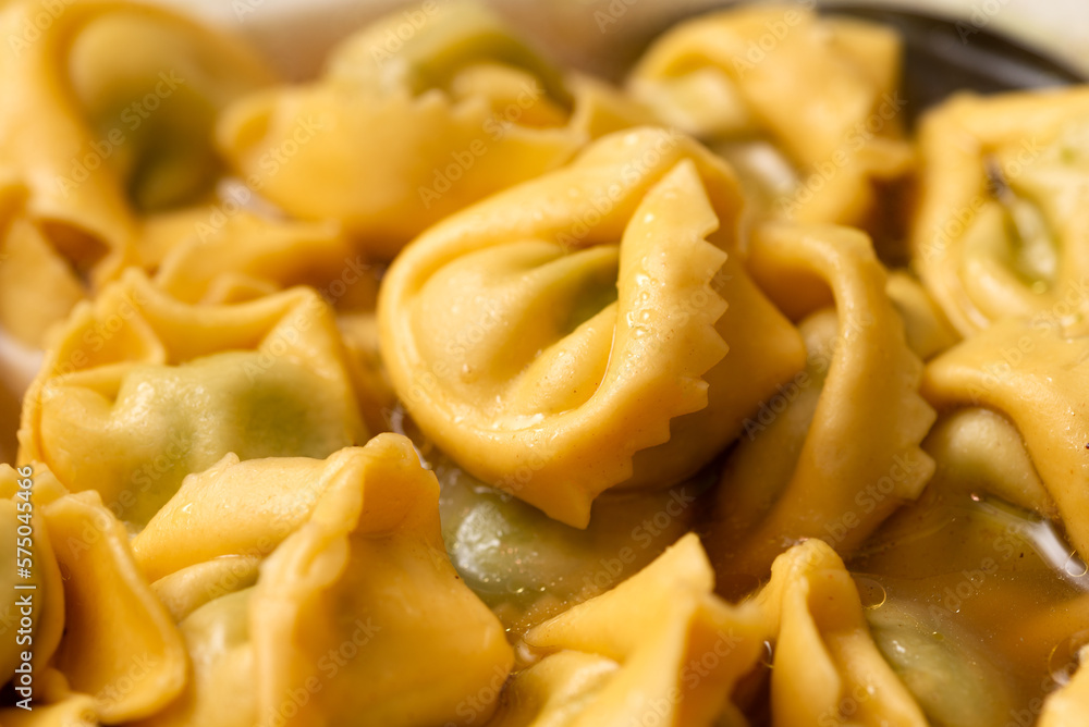 Ripresa ravvicinata di tortellini in brodo ripieni di spinaci, cibo italiano vegetariano Ripresa ravvicinata di tortellini in brodo ripieni di spinaci, cibo italiano vegetariano