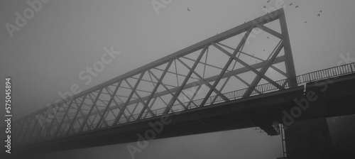 Silhouette of the bridge over river on a misty autumn day