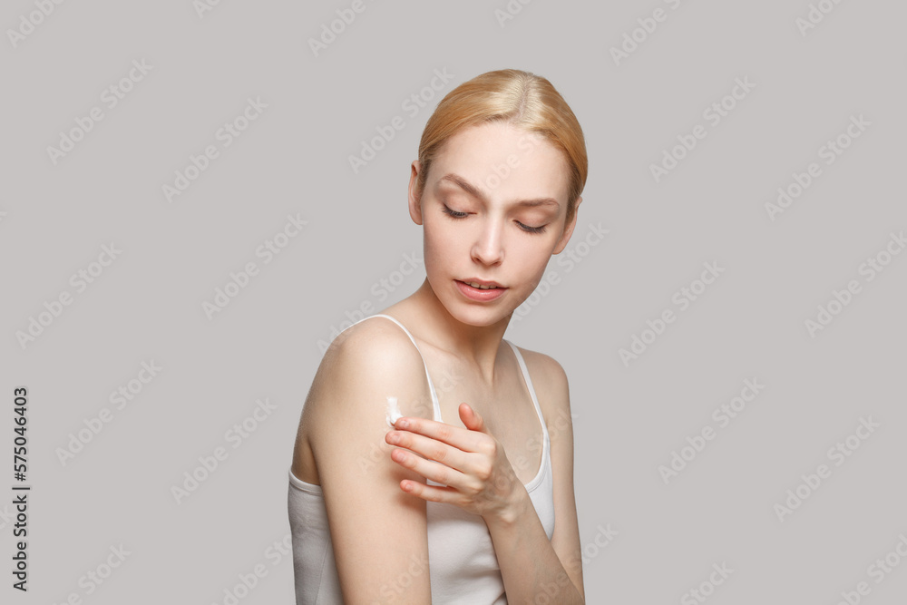 Beautiful woman applying cream on her shoulder Beautiful woman applying cream on her shoulder