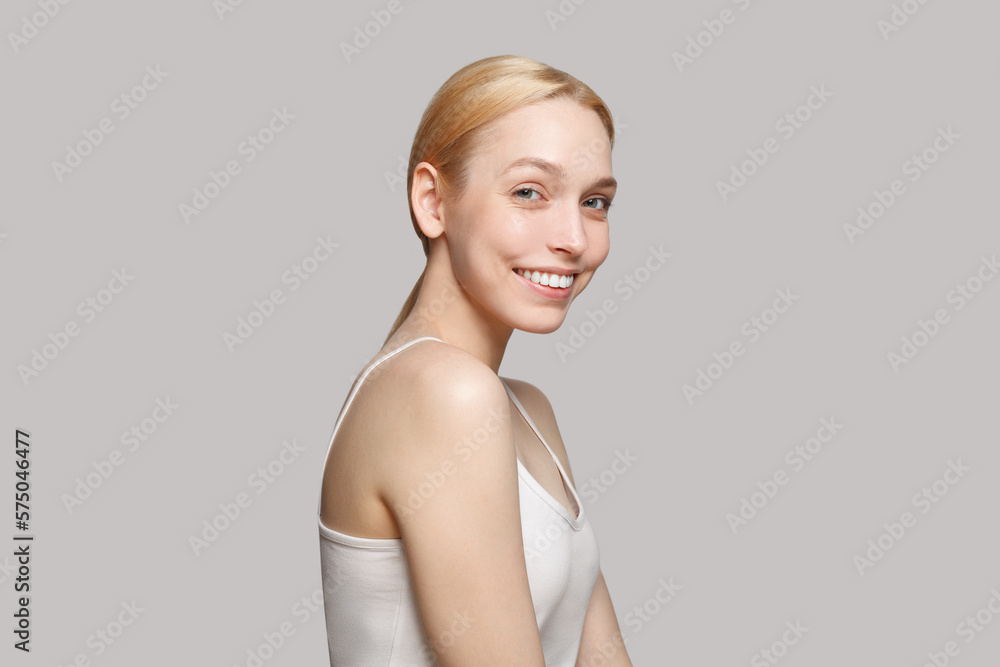 Blonde woman in white top smiling isolated on grey background. Beauty, cosmetics, skincare, glamour Blonde woman in white top smiling isolated on grey background. Beauty, cosmetics, skincare, glamour