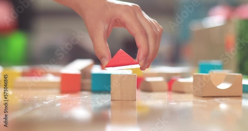 Close-up of girl's hand building house with wooden blocks