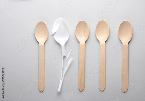 Broken plastic spoon and wooden spoons on a gray background. Plastic free, recycling, eco concept © splitov27