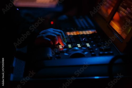 Stage lighting technician working on concert. Professional lights engineer using lights controller desk on music festival