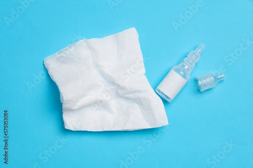 Eye drops bottle with napkins on a blue background. Top view