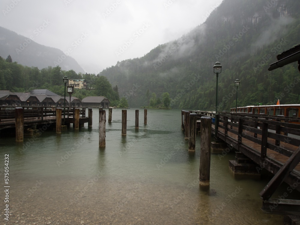 Cruise boat landing on Königssee lake on a cold, rainy, foggy day in May. The Königssee is a natural lake in the Berchtesgaden National Park in Bavaria, Germany. 