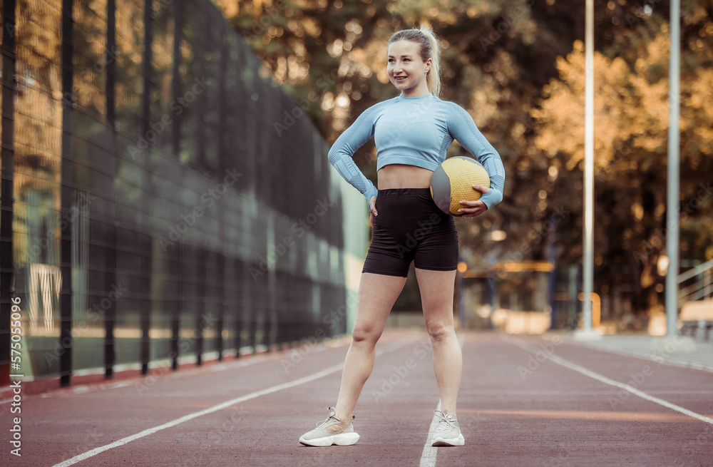 Young athletic woman in sportswear with medicine ball  at the stadium