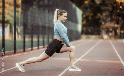 Athletic woman doing warm-up before training at the stadium. Healthy lifestyle