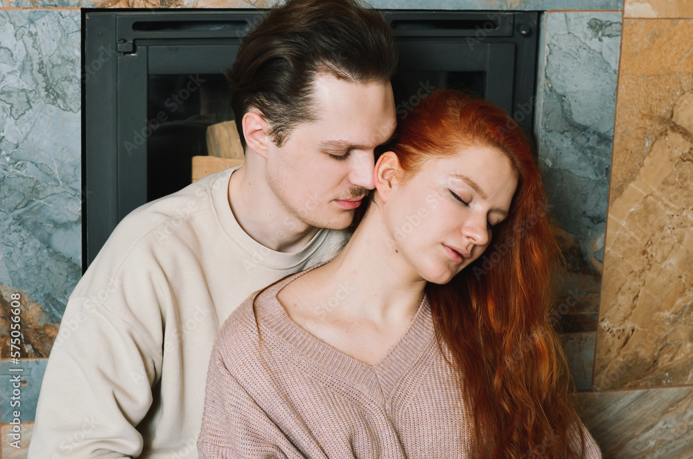 Lovely couple near the fireplace at home. A boy kisses a girl Lovely couple near the fireplace at home. A boy kisses a girl