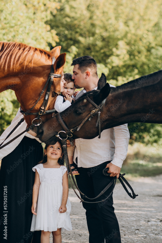Young family with kids having fun with horse in forest
