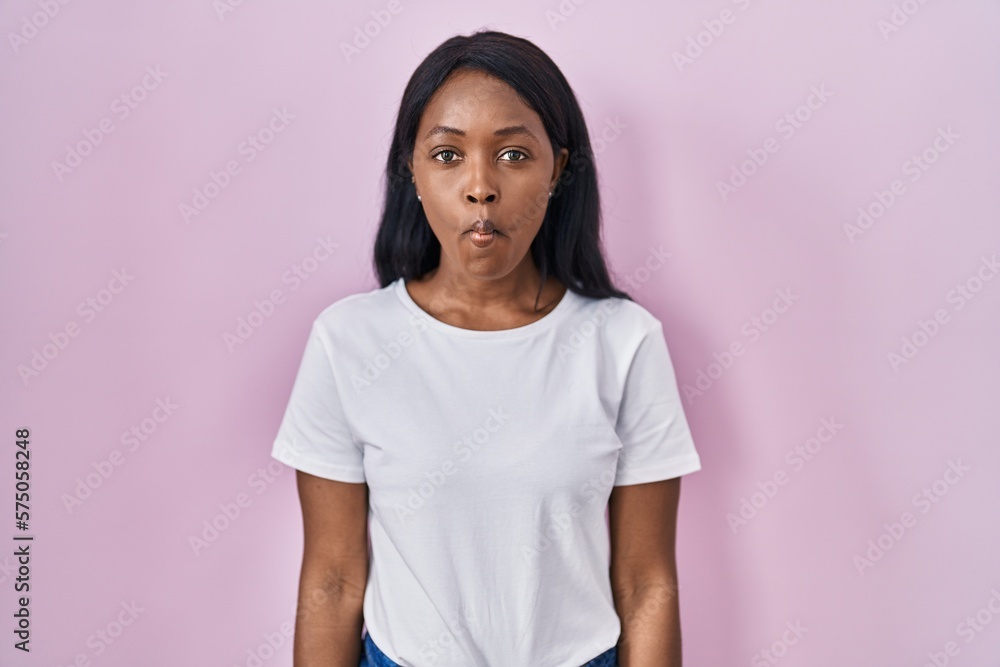 African young woman wearing casual white t shirt making fish face with lips, crazy and comical gesture. funny expression. African young woman wearing casual white t shirt making fish face with lips, crazy and comical gesture. funny expression.