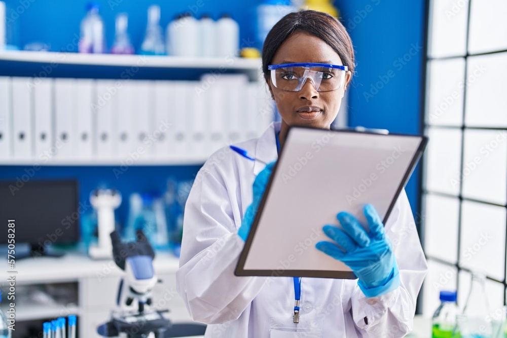 Young african american woman scientist writing on document at laboratory Young african american woman scientist writing on document at laboratory