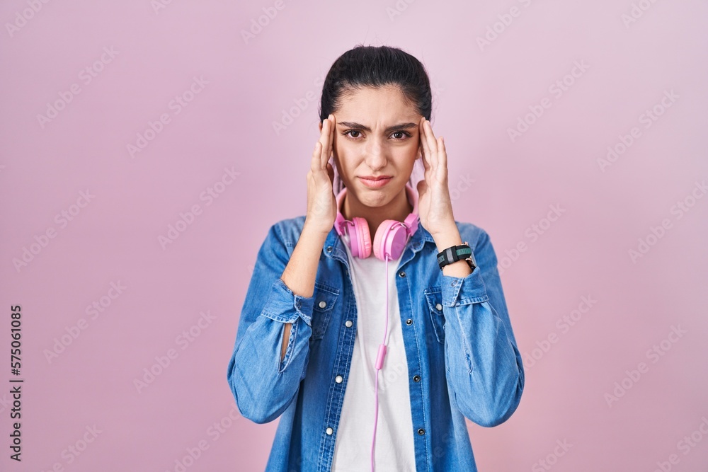 Young beautiful woman standing over pink background with hand on head for pain in head because stress. suffering migraine. Young beautiful woman standing over pink background with hand on head for pain in head because stress. suffering migraine.