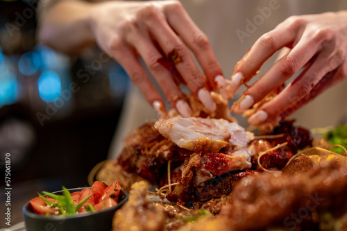 hungry woman hand holding and eatting fried chicken meat in pub