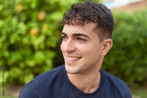 Young hispanic man smiling confident looking to the side at park
