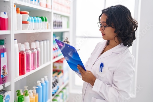 Young beautiful hispanic woman pharmacist writing on document at pharmacy © Krakenimages.com