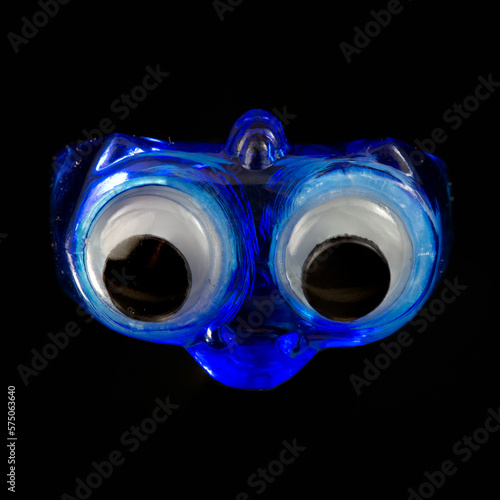 Blue googly eye toy ring on black background